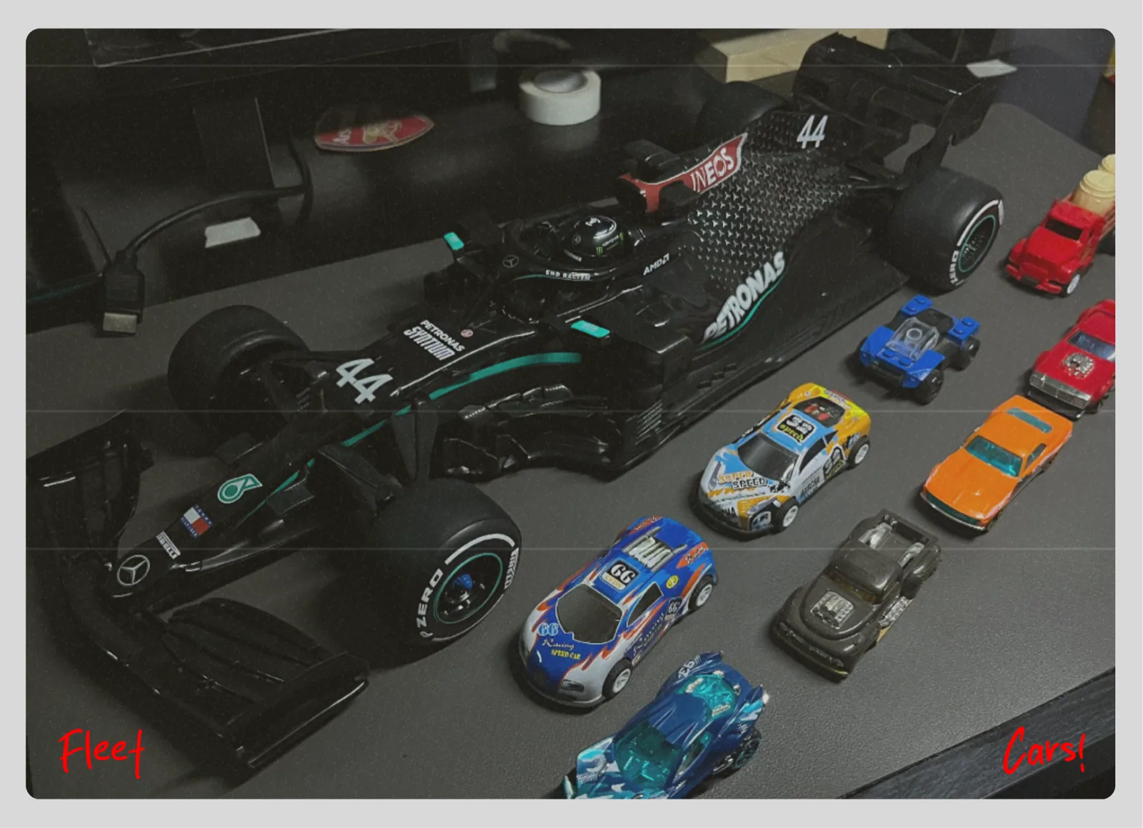 A die-cast Mercedes Formula One car beside a row of toy cars